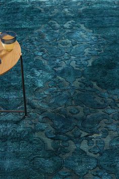 a blue rug with an abstract design on it and a wooden table next to it