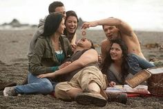 a group of people sitting on top of a beach next to each other