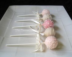 some cake pops are sitting on a white platter with ribbon and bowknots