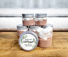 several jars filled with marshmallows on top of a wooden table