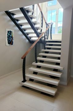 there is a white staircase with black handrails