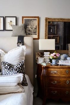 a bedroom with white bedding and pictures on the wall above it's headboard