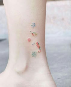 a woman's foot with small tattoos on the side of her body and flowers