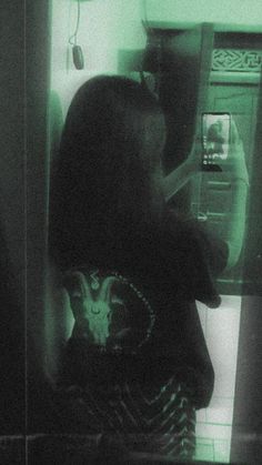 a person standing in front of a refrigerator with green light coming from it's door