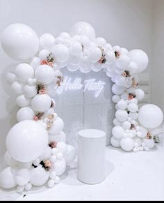 white balloons and flowers are on display in front of an arch with the words hello kitty