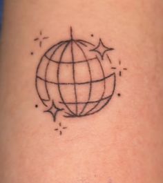 a black and white photo of a small globe tattoo on the leg, with stars around it