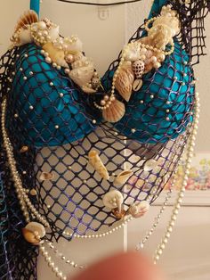 there is a blue bag with shells and pearls on the front, hanging from a hook