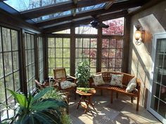 an enclosed patio with wooden furniture and plants in the sunroom, surrounded by glass walls