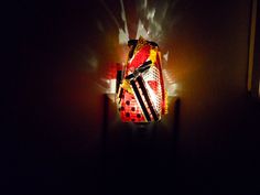 a red and yellow light shines brightly on a dark room with a wall lamp in the corner