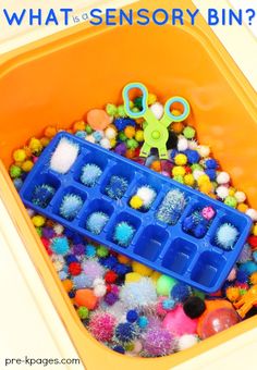 an orange bin filled with lots of different colored balls and plastic scissors on top of it