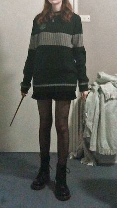 a woman in black and grey striped sweater holding a wand while standing next to a bed