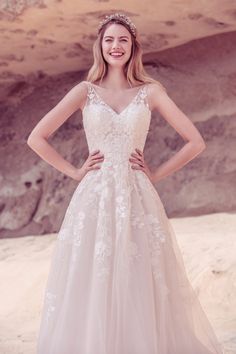 a woman in a wedding dress posing for the camera with her hands on her hips