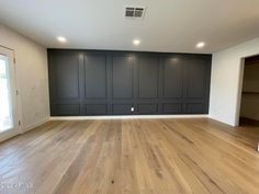 an empty living room with wood floors and dark gray painted walls, along with white trim