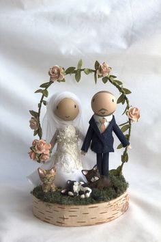 a wedding cake topper with a bride and groom in front of a floral arch