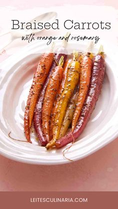 roasted carrots with orange and rosemary on a white plate next to a pink background