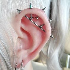 a close up of a person's ear with several piercings on it,