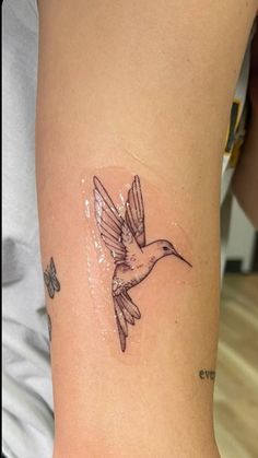 a tattoo on the arm of a woman with a hummingbird in it's beak