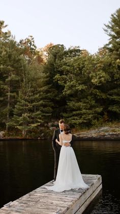 a bride and groom standing on a dock