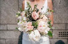 a bride holding a bouquet of white and pink flowers