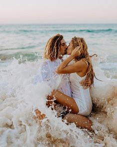 two women are kissing in the water at the beach