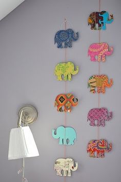 an elephant themed mobile hangs on the wall next to a lamp in a child's room