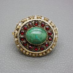 "A one of a kind gilt silver filigree brooch, set with blue / green Eilat stone and reg glass garnets. The brooch is a great quality traditional handwork of a Yemenite Israeli jeweler from 1950's - 1960's. Due to a hidden bale you may choose to wear this item as a brooch or as a pendant. You may choose to buy this item on its own or or with a matching 20 inches (50 cm) gold plated sterling silver rope chain, shown on the photos. The brooch will be shipped in a gift box. A lovely gift idea! The b Heirloom Oval Gemstone Brooches, Antique Brooch With Intricate Pendant Design, Antique Yellow Gold Filigree Brooches, Antique Pendant Brooch With Intricate Design, Antique Oval Gemstone Brooch, Antique Oval Gemstone Brooches, Heirloom Filigree Oval Brooch, Heirloom Style Oval Filigree Brooch, Heirloom Oval Filigree Brooch