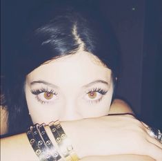 a close up of a person with two bracelets on their arms and one arm wrapped around her face