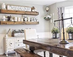 a wooden table sitting in front of a window next to two shelves filled with potted plants