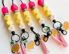 four key chains with fruit and tassels attached to them on a white surface