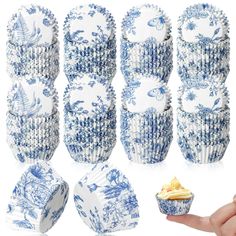 blue and white porcelain dishes are stacked on top of each other, with one being held up by a hand