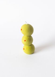 two green apples stacked on top of each other in front of a white background with orange dots