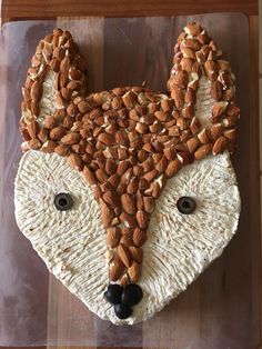 a cake made to look like a fox with nuts on it's face and eyes