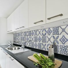 a kitchen with blue and white tiles on the backsplash, counter tops, and sink