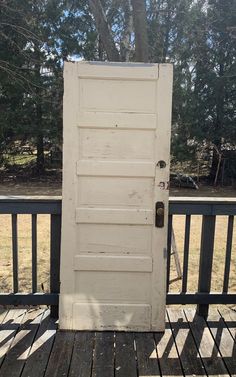 an old white door sitting on top of a wooden deck