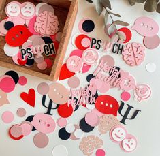 some pink and red paper cutouts are on a table next to a wooden box