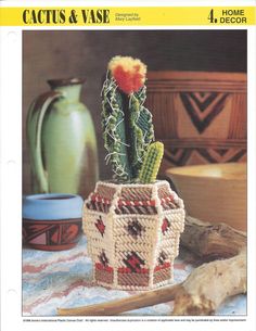 a crocheted cactus in a pot on a table next to some other items