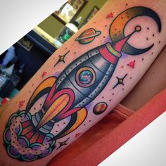 a colorful tattoo on the arm of a woman with a rocket ship and stars around it