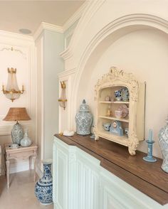 a room filled with blue and white vases on top of a wooden table next to a shelf