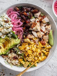 a white bowl filled with chicken, avocado, corn and other food items