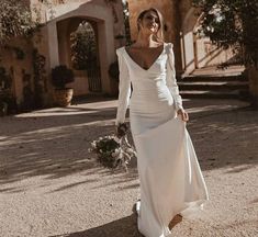 a woman in a white dress is walking down the street with her hand on her hip