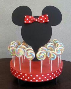 a mickey mouse cake with lollipops in it and a bow on top