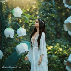 a woman wearing a white dress standing in front of flowers