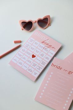 a pink bridal game with sunglasses and pencils on the table next to it