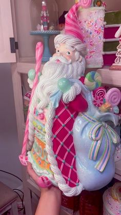 a hand holding a candy santa figurine in front of a shelf