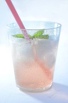 a glass filled with liquid and a pink straw sticking out of it's top