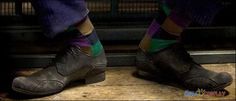 the legs and feet of a person wearing black shoes with multi - colored striped socks