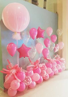 pink and white balloons are arranged in a row on the wall next to a balloon arch