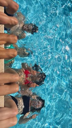 several people are standing in the middle of a swimming pool with their feet up to the water's edge