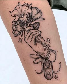 a black and white photo of a tattoo with flowers on the arm that has a ribbon around it