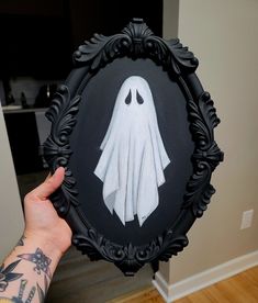 a person holding up a black and white frame with an image of a ghost in it